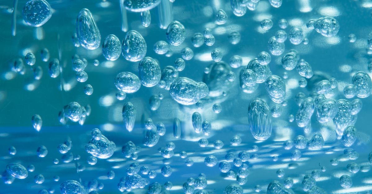 Bubbles of many different sizes suspended in a blue gel, seen up close.