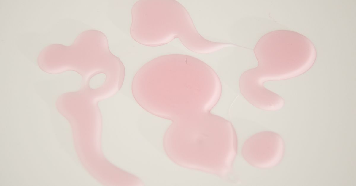 Blobs of pale pink gel pooled in irregular shapes across a white surface.