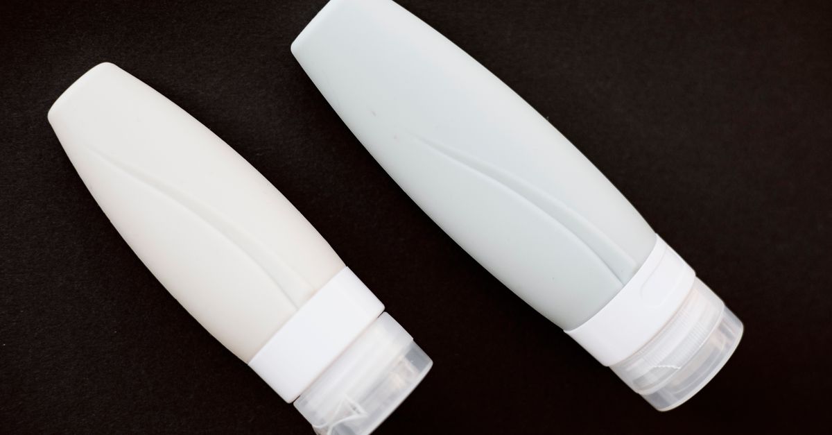 Two identical white plastic tubes lie side by side on a black surface.
