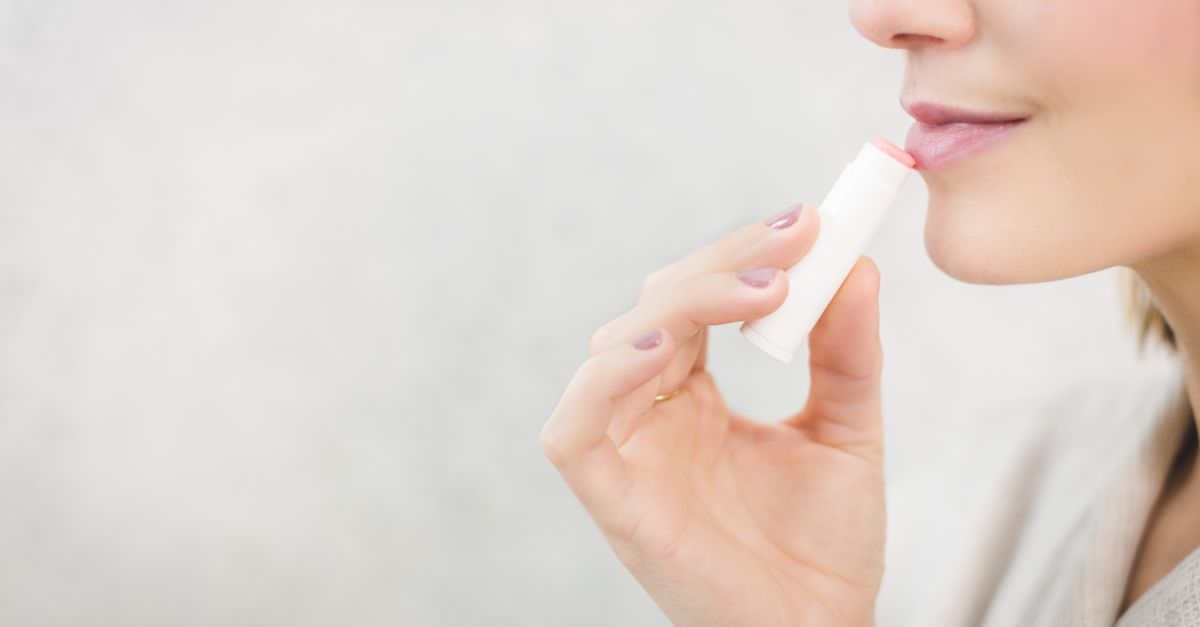 A close-up of someone about to apply a small tub of lip balm.
