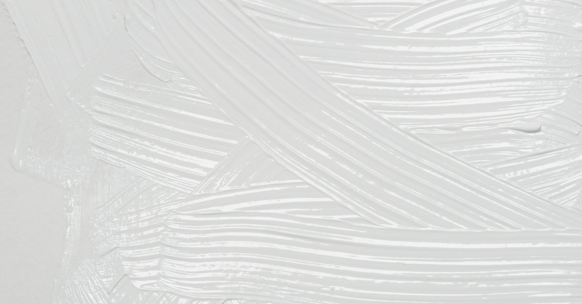 Thick white strokes of a matte paste crisscross a pale surface, filling the frame.