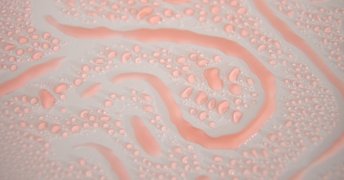 Pink gel spread thin across a white surface, dense with small bubbles and winding channels.
