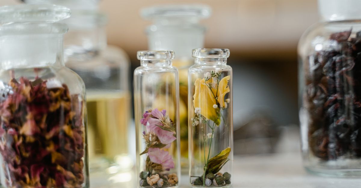 A row of small clear glass vials, each holding different dried petals and flowers.