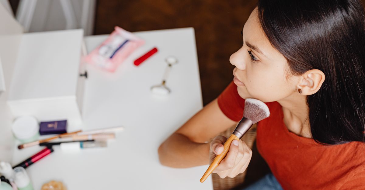 An overhead view of a person applying makeup with a brush at a vanity table.