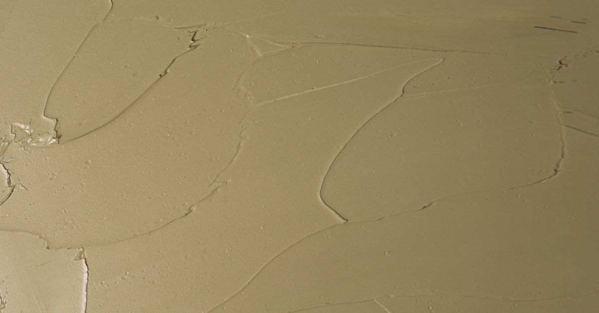 A film of pale amber jelly smeared across a surface, with thin cracks where it was dragged.