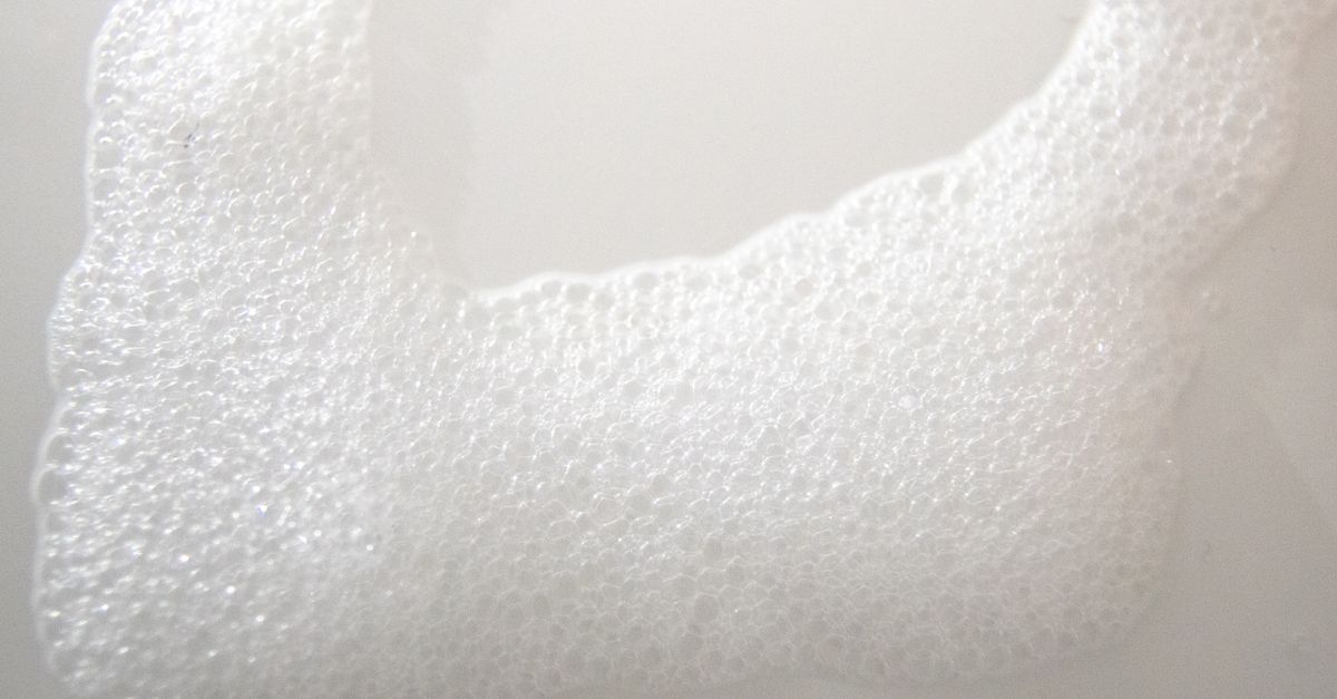 A thick band of fine white foam stretches across a white surface.