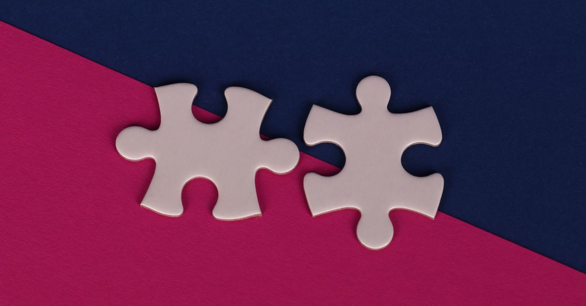 Two pale puzzle pieces sit side by side without interlocking, on a ground split diagonally into magenta and navy.